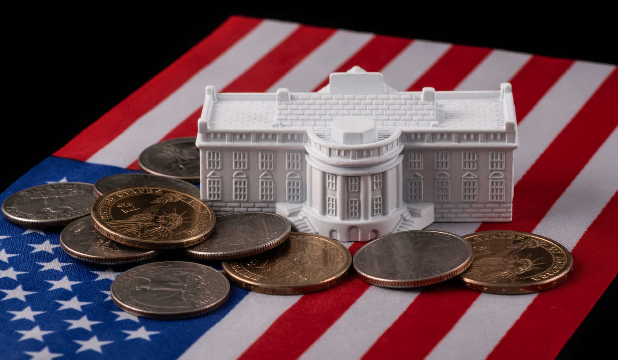 Tiny plastic White House with pennies surrounding it.